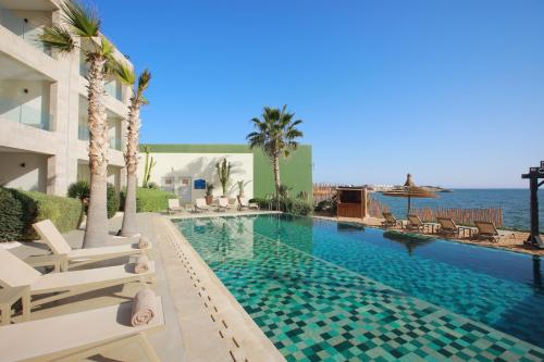 a swimming pool with chairs and the ocean in the background at Dakhla South Bay, WorldHotels Distinctive in Dakhla