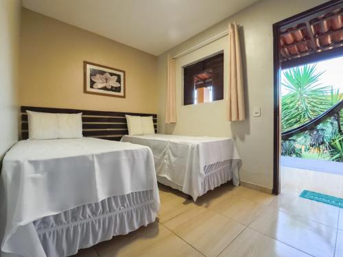 a bedroom with two beds and a window at Pousada pôr do sol in Riachuelo