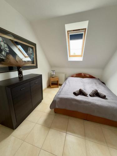 a bedroom with a bed and a dresser and a window at Marilyn Apartman Gyenesdiás in Gyenesdiás
