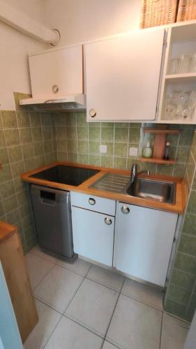 a small kitchen with white cabinets and a sink at Studio Algarve in Middelkerke