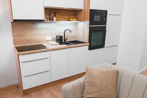 a kitchen with white cabinets and a counter top at Tímár 18 Apartman in Pécs