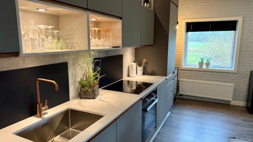 a large kitchen with a sink and a window at Kastanjegaarden in Ansager