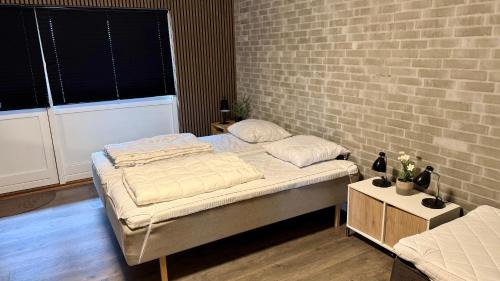 a bedroom with two beds and a brick wall at Kastanjegaarden in Ansager