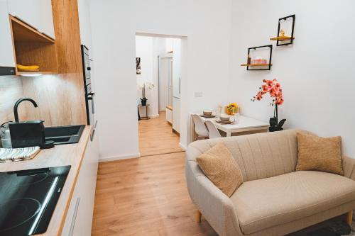 a living room with a couch and a kitchen at Tímár 18 Apartman in Pécs