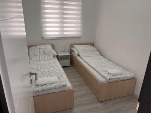 two beds in a small room with a window at Apartman M&D in Neum