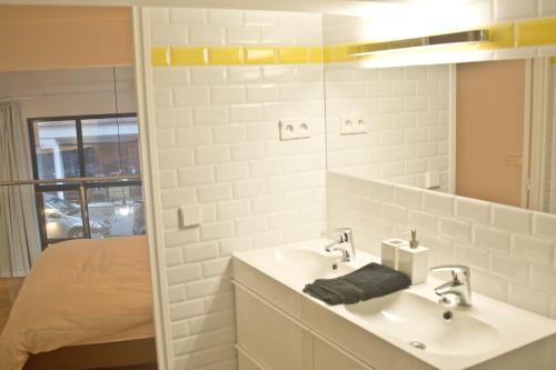 une salle de bain avec un lavabo, un miroir et un lit dans l'établissement Chez vous - Marguerite et Emile, à Paris