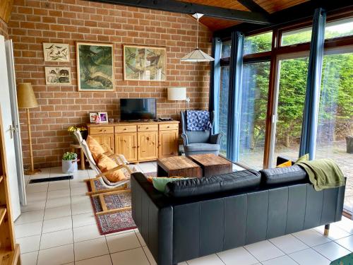a living room with a black couch and a brick wall at Boerenslag 46 in Sint Maartenszee
