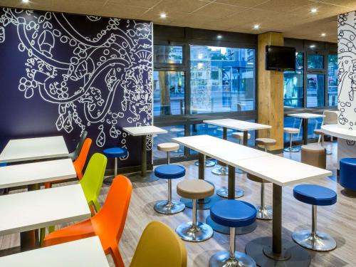 a cafeteria with tables and chairs and a tv at Ibis Budget Marseille Timone in Marseille