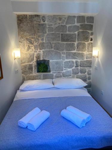 a bed with two white pillows and a stone wall at Milea in Makarska