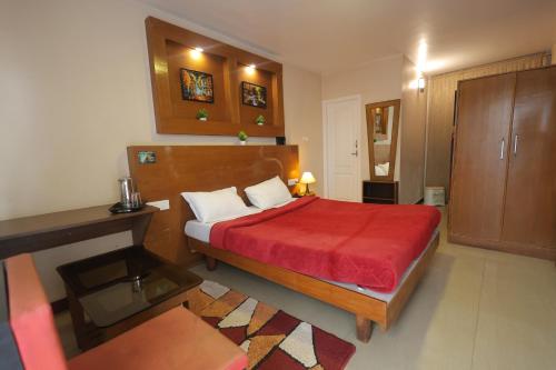 a bedroom with a bed with a red bedspread at Drizzle Drop Inn in Ooty