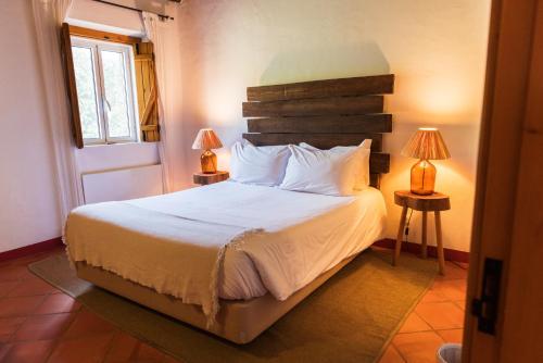 a bedroom with a bed with two lamps on two tables at Casas de Juromenha in Juromenha