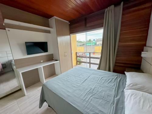 a bedroom with a bed and a large window at Hotel 5km da Guarda do Embaú in Palhoça