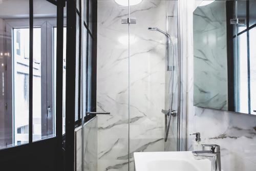 a bathroom with a sink and a glass shower at Le charmant, Hyper Centre Angers in Angers