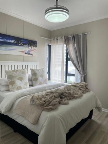 a bedroom with a large white bed with a large window at Beachside Bliss Strand in Strand