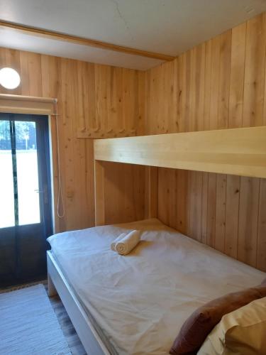 a bed in a room with a wooden wall at Vastseliina Metskond Camping in Vahtseliina