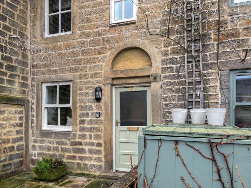 a brick building with a door and three white buckets at Candy Cottage in Addingham