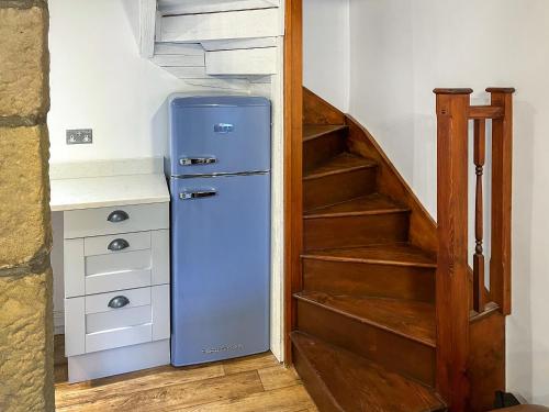 a blue refrigerator in a room with a staircase at Candy Cottage in Addingham