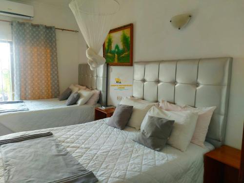 a bedroom with two beds with white sheets and pillows at Samfya waterfront lodge 