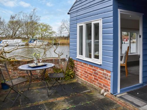 a blue house with a table and chairs outside at Riverside Retreat in Beccles