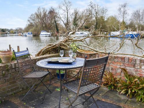 a table and chairs sitting next to a body of water at Riverside Retreat in Beccles