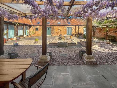 a courtyard with a table and benches and purple wisterias at Meadow View Broadlea in Stokeham