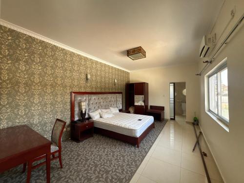 a bedroom with a bed and a table and a window at Hotel Izzy Stay in Maputo