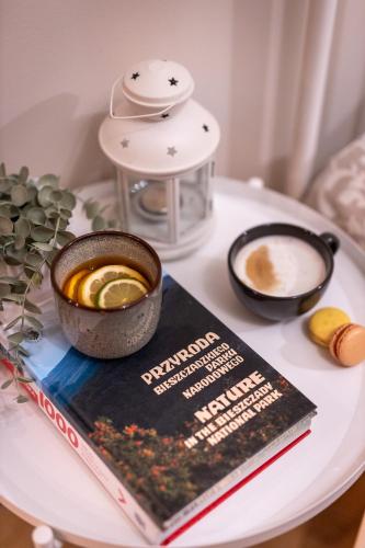 a book and a cup of coffee on a table at Villa Kasztelan Apartamenty in Ustrzyki Dolne