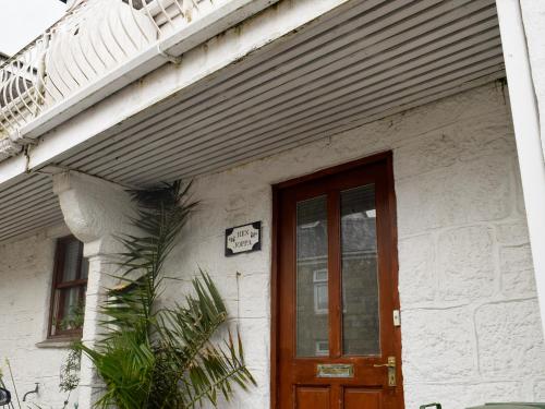 a white building with a door and a sign on it at Hen Joppa in Newlyn
