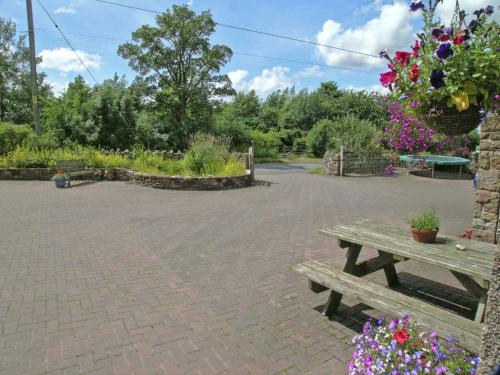 a wooden bench sitting in a courtyard with flowers at Rundales Cottage in Appleby