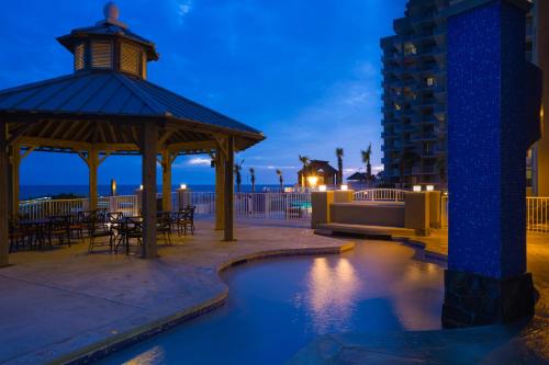 a gazebo with a table and chairs and a building at Escapes! To The Shores Orange Beach, A Ramada by Wyndham in Orange Beach
