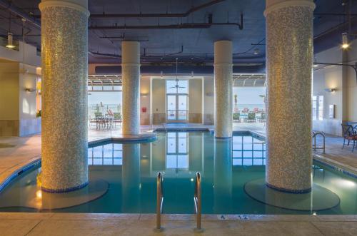 a pool with columns and chairs in a building at Escapes! To The Shores Orange Beach, A Ramada by Wyndham in Orange Beach