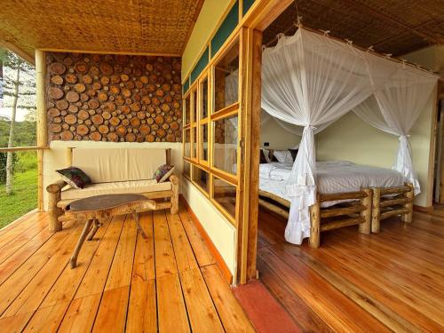 a bedroom with a bed and a couch on a wooden floor at Kibale Riverside Camp in Kamwenge