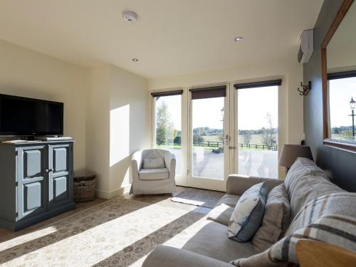 a living room with a couch and a tv at Cow Pasture Cottage in Hallington