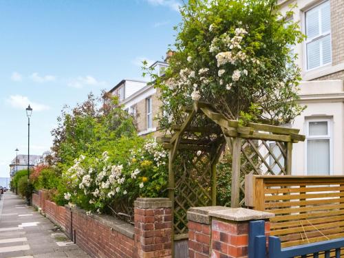 a garden in front of a house with a wooden bench at Longsands Retreat in Tynemouth