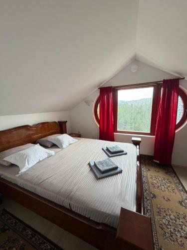 a bedroom with a bed with red curtains and a window at Vila Milka in Lepterija