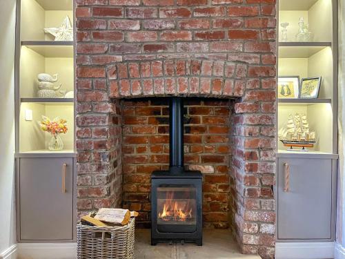 a brick fireplace with a stove in a room at Longshore in Runswick