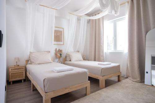 a white bedroom with two beds and a window at Casa Rosa Sé - Luxury Boutique Guest House in Faro