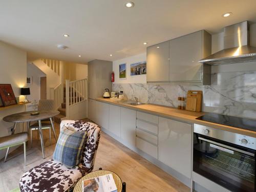 a kitchen with white cabinets and a table and a chair at Hope Cottage - Uk40055 in Aberfeldy