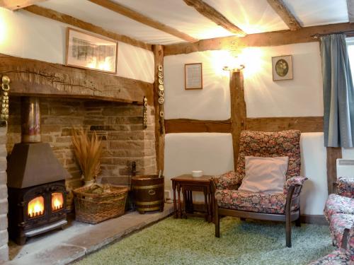 a living room with a fireplace and a chair at Hollywall Croft in Stoke Prior