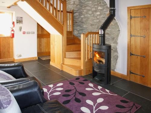 a living room with a fireplace and a staircase at Bwthyn Celyn-Oa6 in Ystrad Meurig