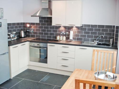 a kitchen with white cabinets and a wooden table at Bwthyn Celyn-Oa6 in Ystrad Meurig
