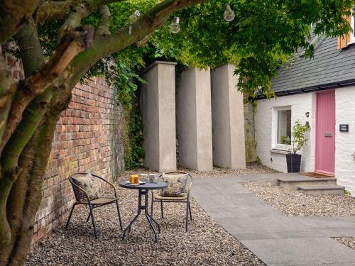 a table and two chairs next to a brick wall at Harris Cottage - Uk40056 in Aberfeldy
