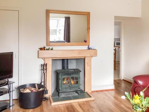 a wood stove in a living room with a mirror at Keepers Cottage - Uk51549 in Kirktown of Auchterless