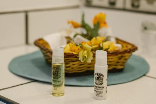 two bottles of liquids sitting on a counter with a basket of flowers at Gringo Bill's Boutique Hotel in Machu Picchu