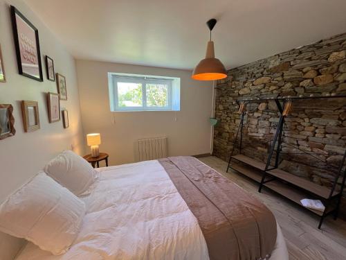 a bedroom with a bed and a stone wall at L'échappée in Neulliac