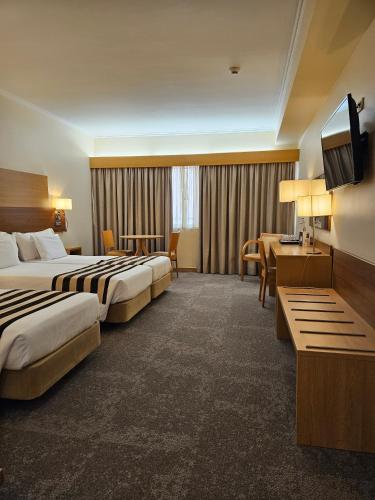 a hotel room with two beds and a flat screen tv at Hotel Principe Lisboa in Lisbon