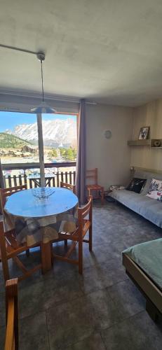 a living room with a table and a bed at Studio lumineux et cosy avec vue montagne 7è étage in Superdevoluy