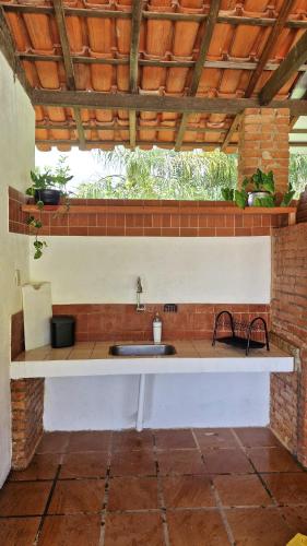 a kitchen with a sink and a brick wall at Sítio Toca da Pedra in Pedra Bela