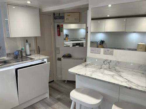 a white kitchen with white counters and white cabinets at Ship Cottage Tenby Beach 50m in Pembrokeshire
