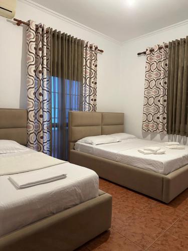 two beds in a room with curtains at Guesthouse Enea in Durrës